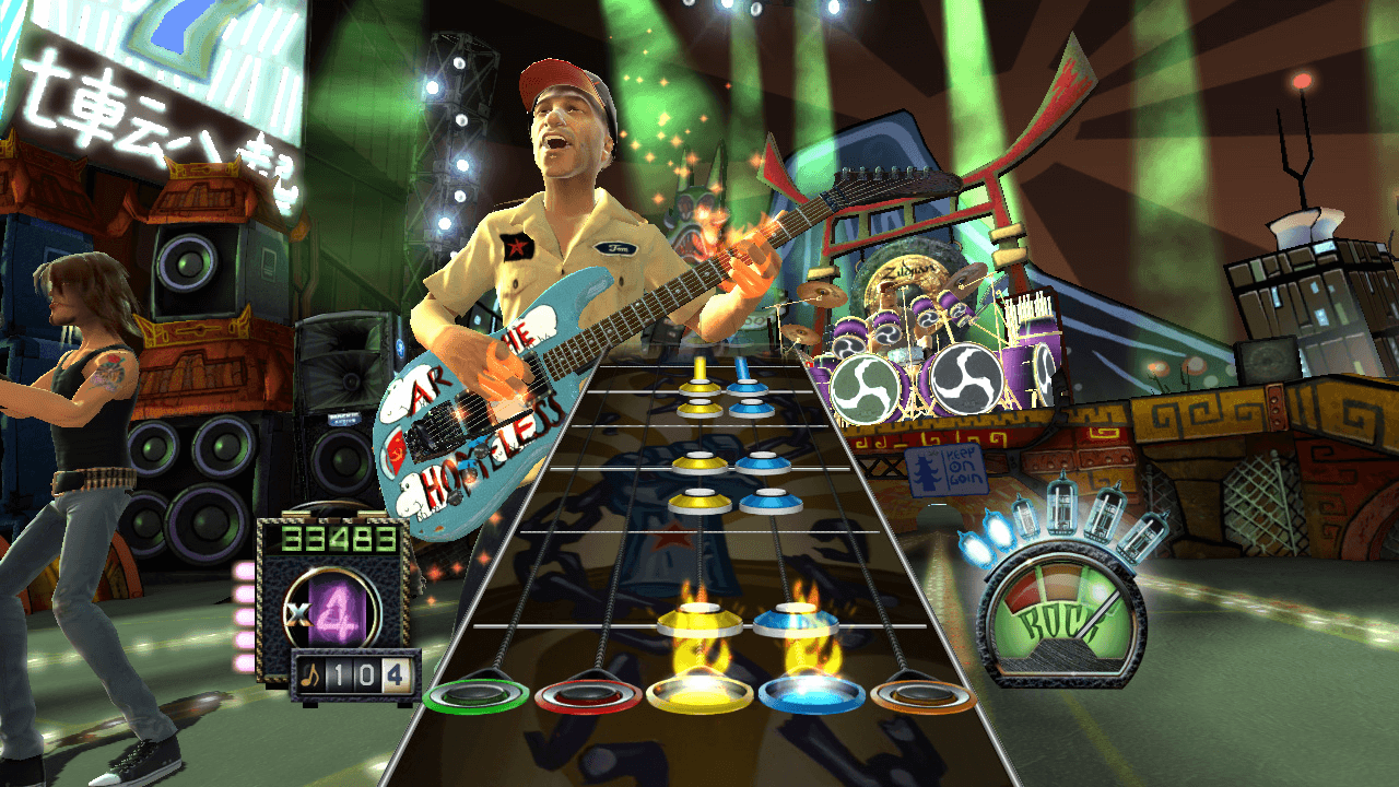Screenshot from the video game Guitar Hero, included as a reference - coloured notes travel down a fretboard towards a fixed strike line at the bottom of the screen